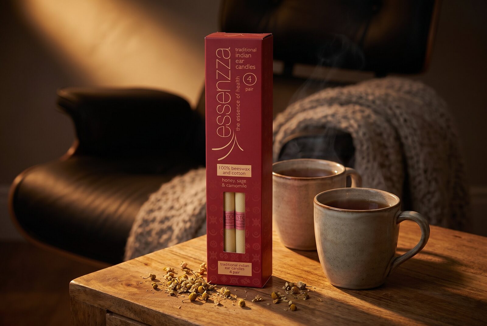 Essenzza Traditional Indian ear candles pack still-life — crimson carton with honey sage and camomile on a warm-timber side table